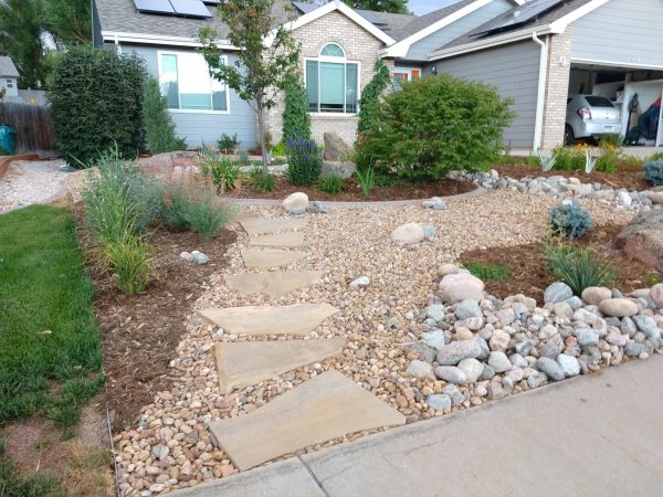 green and brick house with xeriscape garden and flagstone path