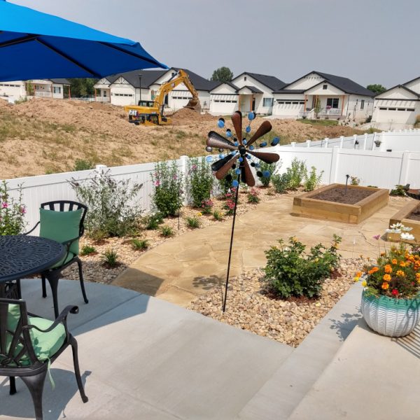construction equipment in the distance, raised vegetable bed, patio furniture, flagstone walkway